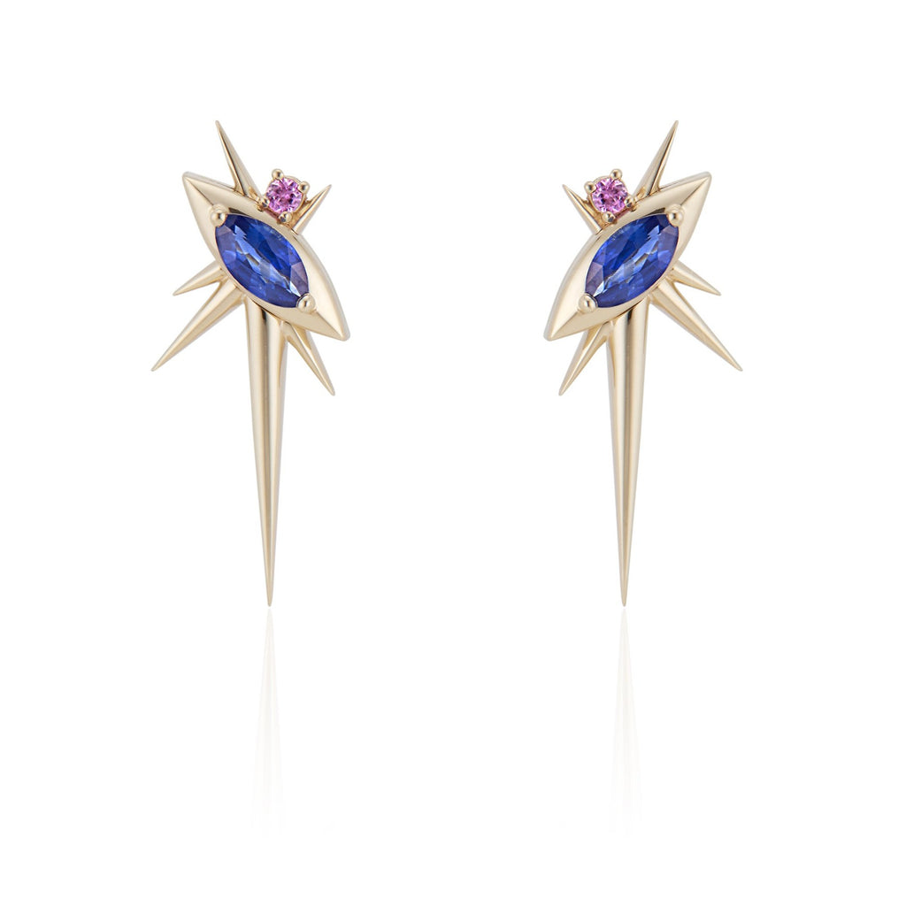Front view of alternative drop earrings, each with 1 marquise-shaped blue sapphire, set at a 45-degree angle, with a small pink sapphire above. 6 yellow gold spikes of varying lengths extend from the setting, with a large, long spike pointed down. 