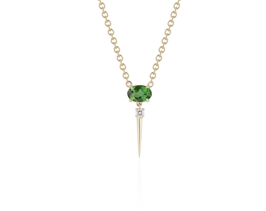 Front view of tsavorite drop necklace. A horizontal oval-shaped tsavorite is fixed with 4 prongs to a yellow gold round-link chain. Below this, a single link connects to a small round diamond with a dramatic yellow gold spike dropping down. 