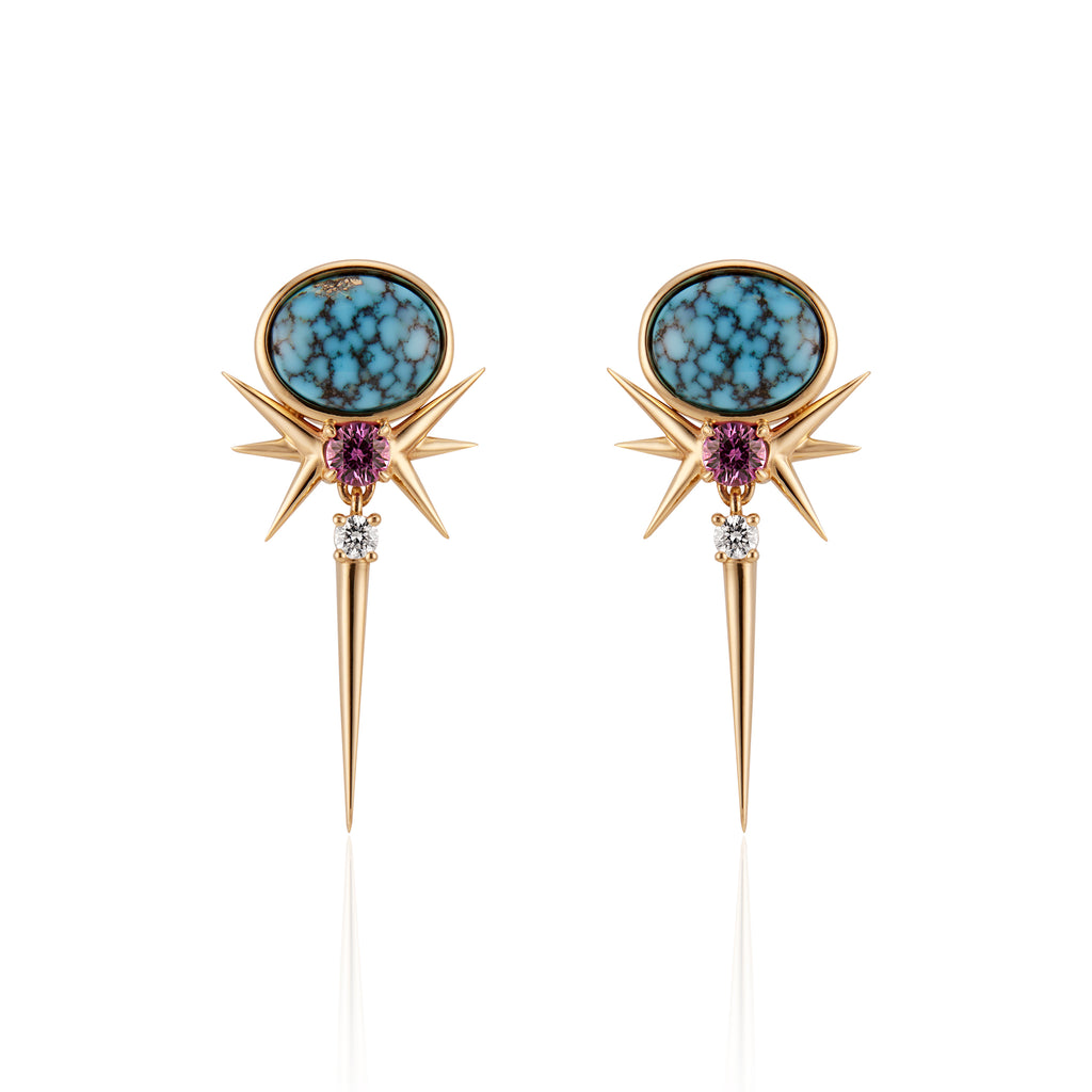 Front view. Spike drop earrings with 1 oval-shaped turquoise stone on the head of the drop spike. 6 spikes protrude out of a small fuchsia sapphire set below the turquoise. Just below the fuchsia sapphire along the long vertical spike is a small brilliant-cut diamond.
